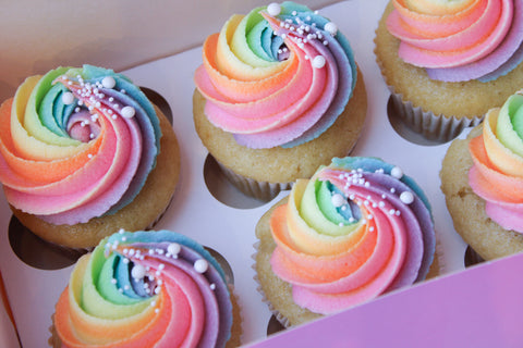 Kleurrijke rainbow cupcakes met vrolijke topping en sprinkles
